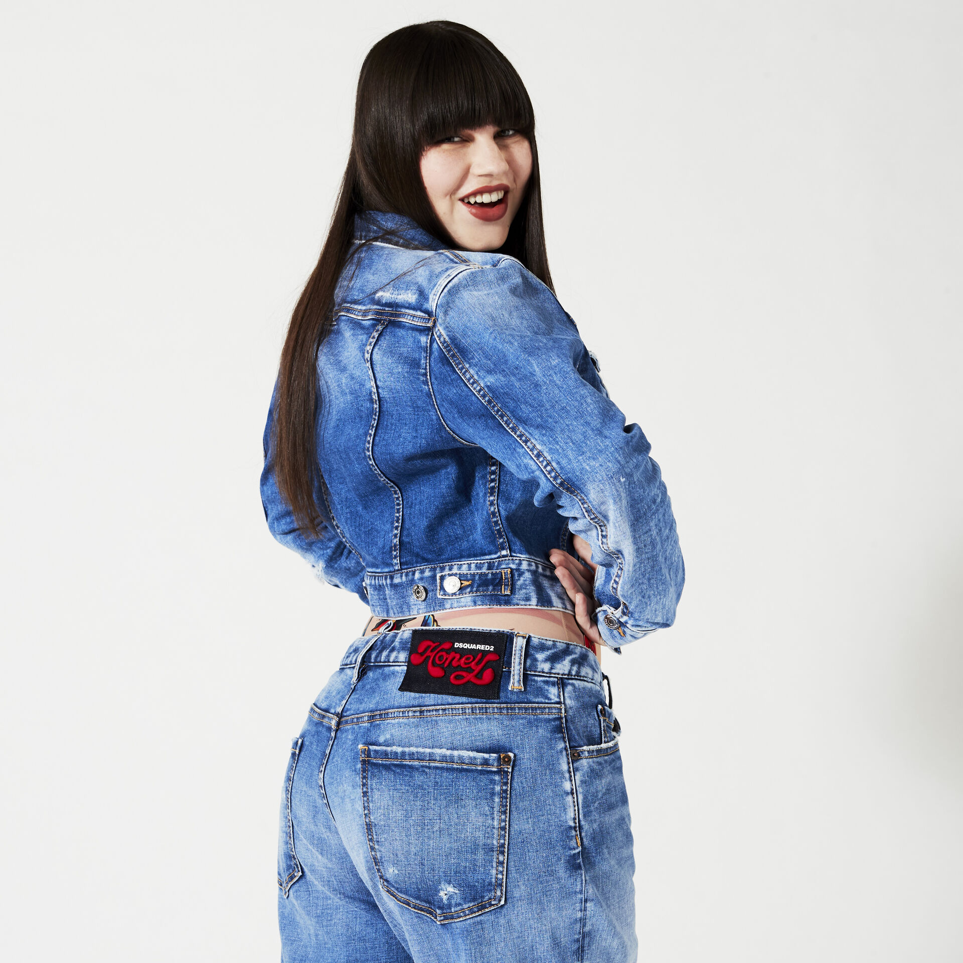Woman with long brunette hair wearing a denim jacket and light blue jeans